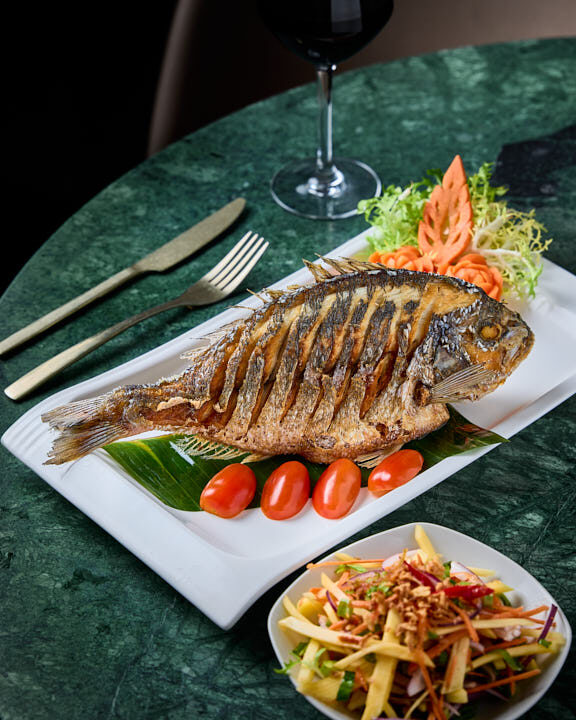 Bar ou Daurade Royale entière frit à la mangue verte sur une feuille de bananier