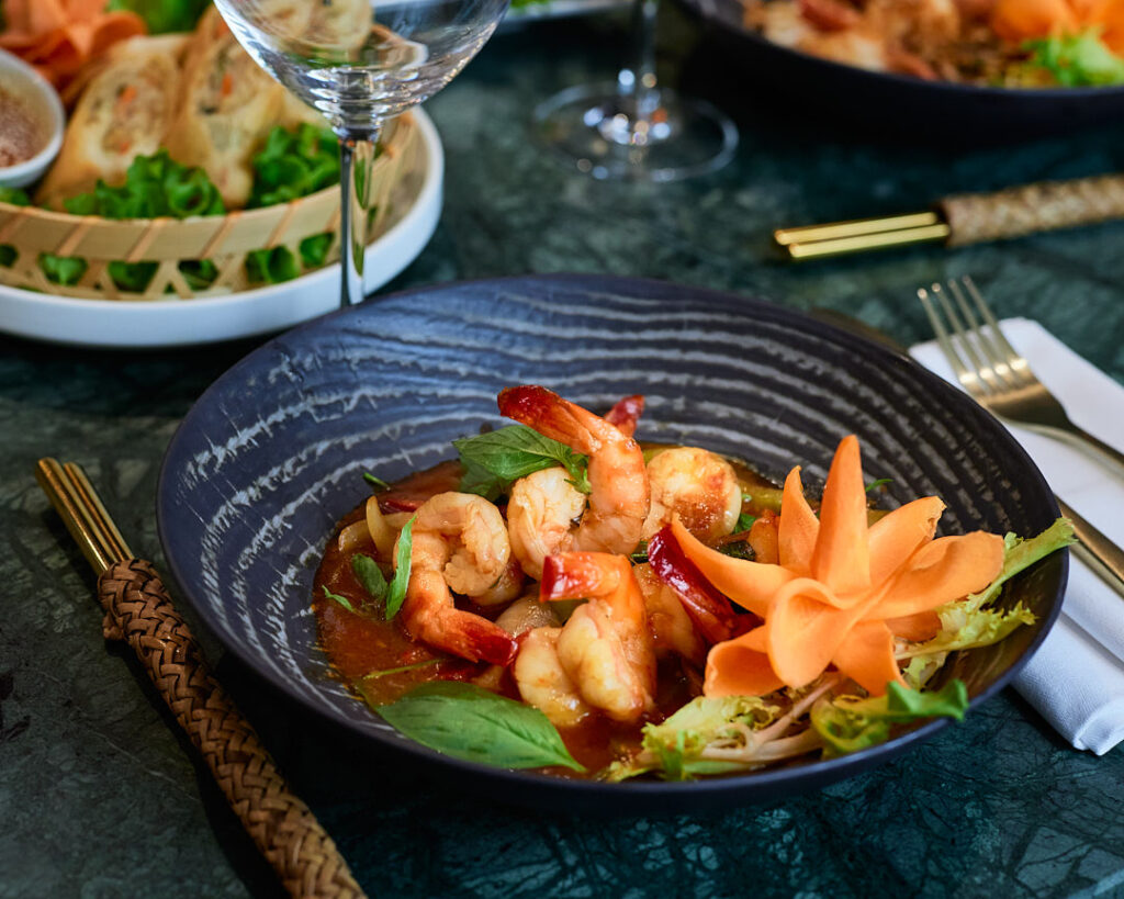 Table en marbre verre dressées de plats thaïlandais et crevettes au basilic.