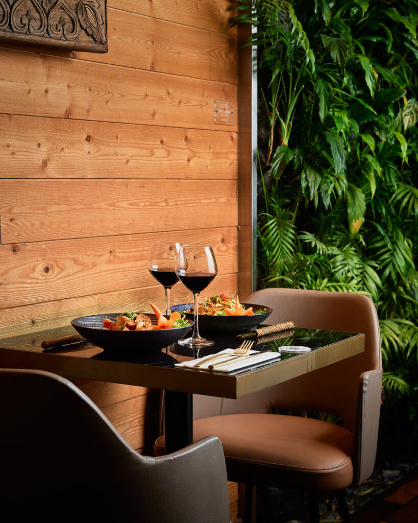 Table en marbre noir dressées de plats thaïlandais avec murs végétal.