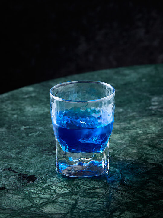 Cocktail Suan kiss au curaçao bleu sur une table en marbre vert