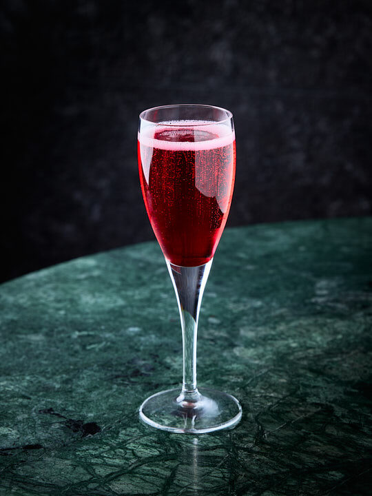 Cocktail Miss Chang Mai dans une flute a champagne sur une table en marbre vert